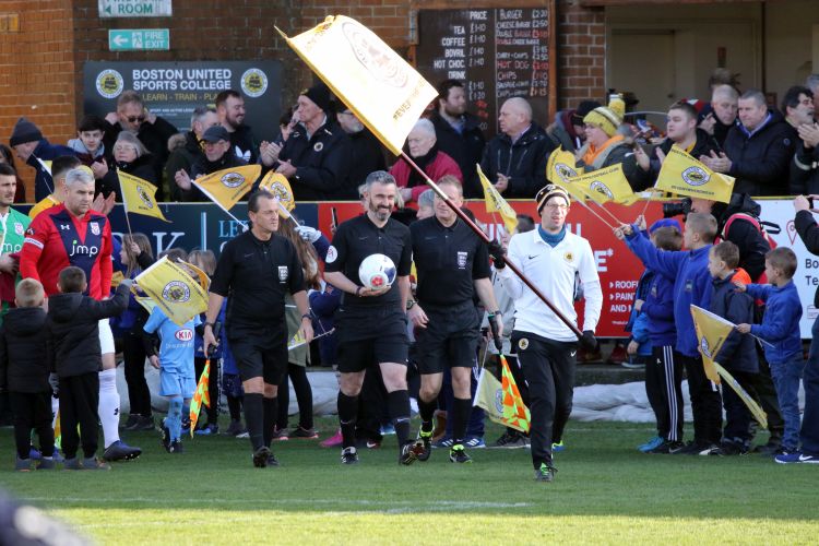 The officials and teams are led out behind the flag